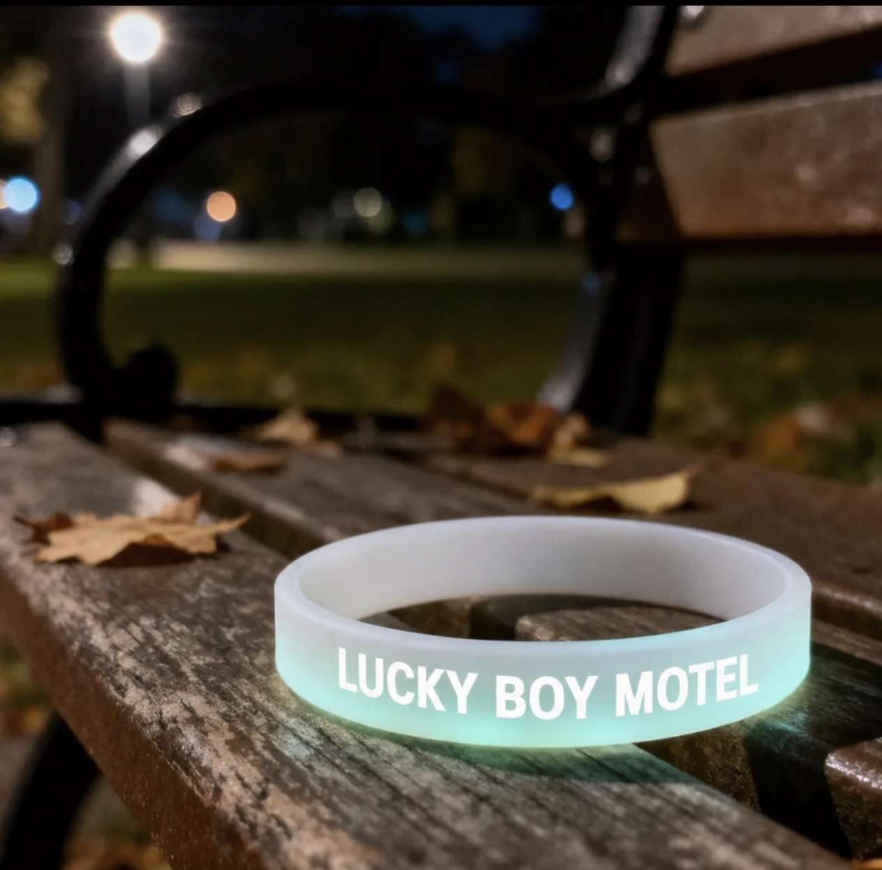 White glowing Lucky Boy Motel wristband on a bench at night.